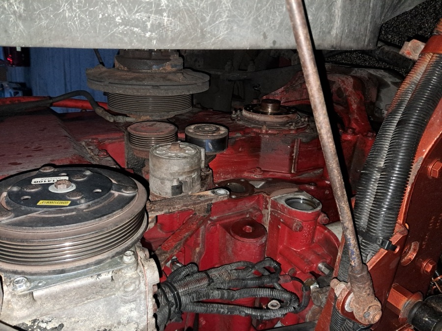 Close-up of a red diesel engine showing pulleys and serpentine belt components during repair